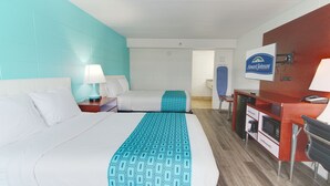 Ein Hotelzimmer mit zwei Betten, einem Schreibtisch, einer Mikrowelle und einem Fernseher.
