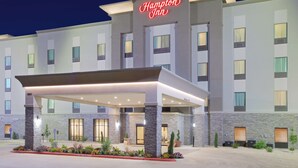 A Hampton Inn hotel with a covered entrance, stone pillars, and a well-lit facade.