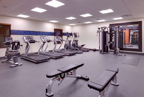 Een fitnessruimte met loopbanden, crosstrainers en gewichten.
