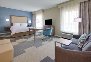 Een hotelkamer met een bed, bureau, stoel, bank en een televisie.