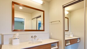 A modern bathroom with a large mirror, two sinks, and wooden vanity cabinets.