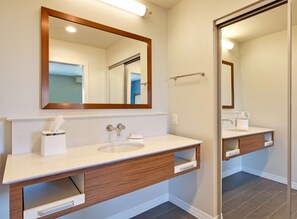 A modern bathroom with a large mirror, two sinks, and wooden vanity cabinets.