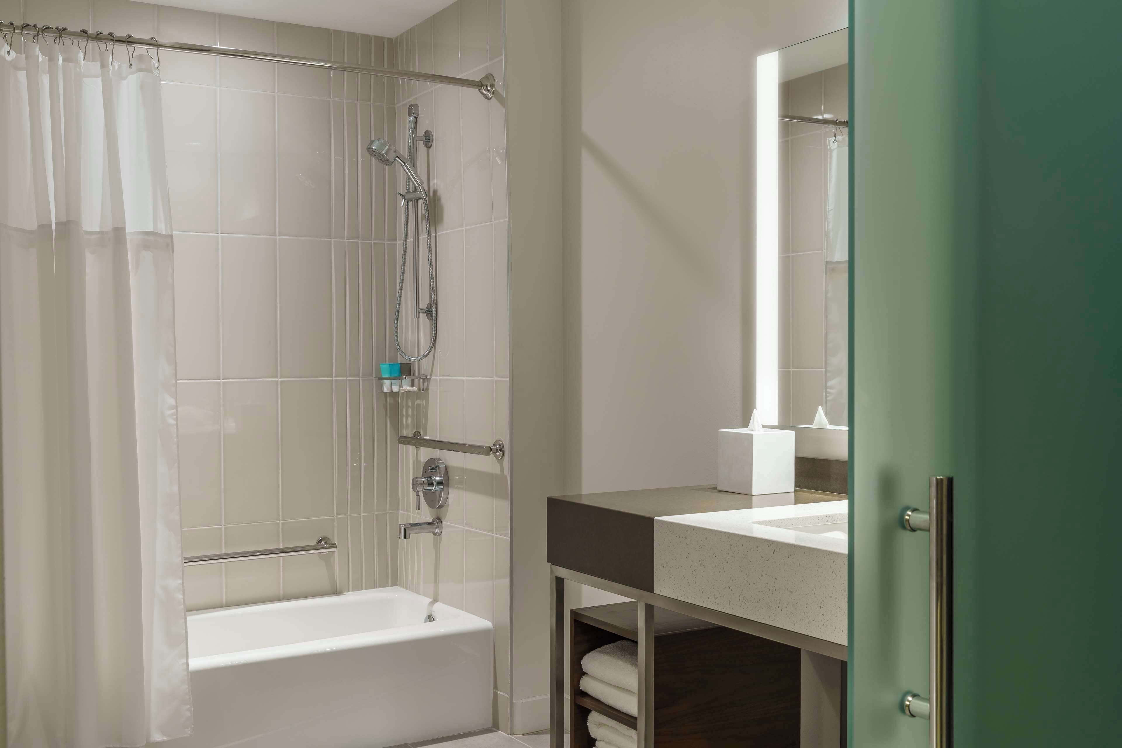 A modern bathroom with a glass shower enclosure, a white bathtub, and a vanity with a mirror.