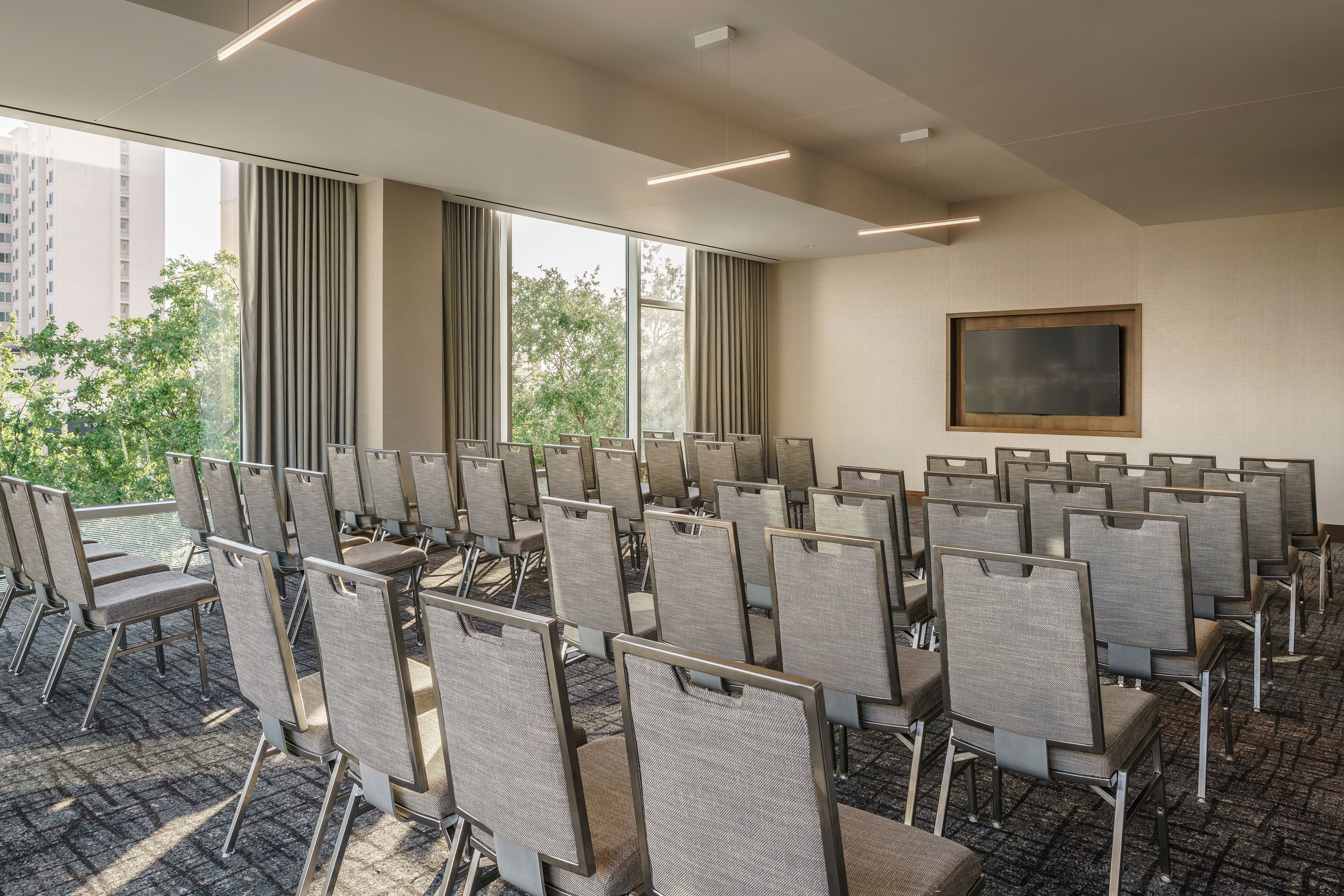 A conference room with rows of chairs, large windows, and a framed picture on the wall.