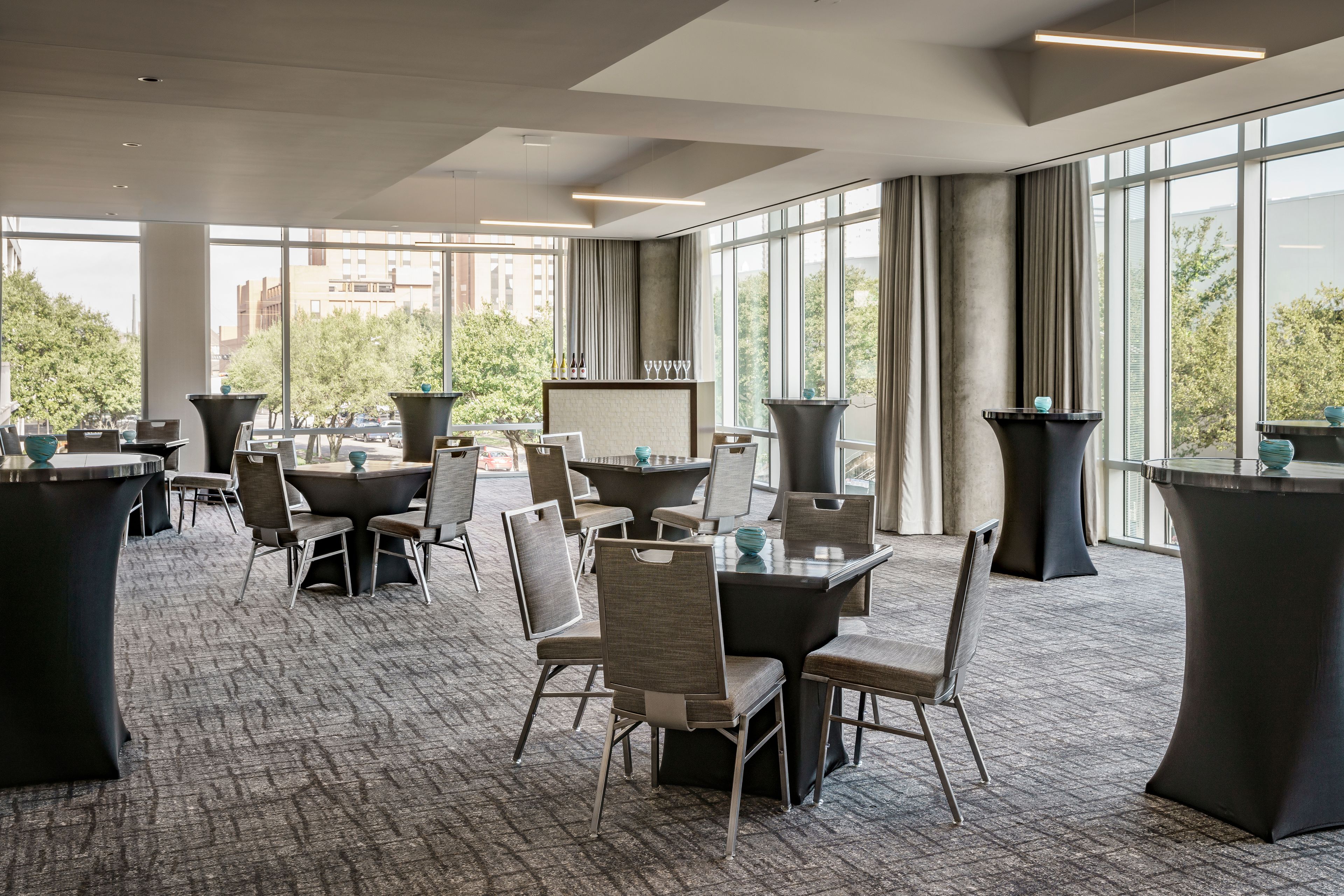 A modern conference room with large windows, multiple tables, and chairs.