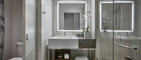 A modern bathroom with a glass shower enclosure, a vanity with a mirror, and a toilet.