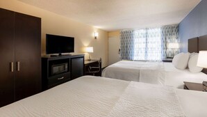 Habitación de hotel con dos camas, televisión, escritorio y armario.