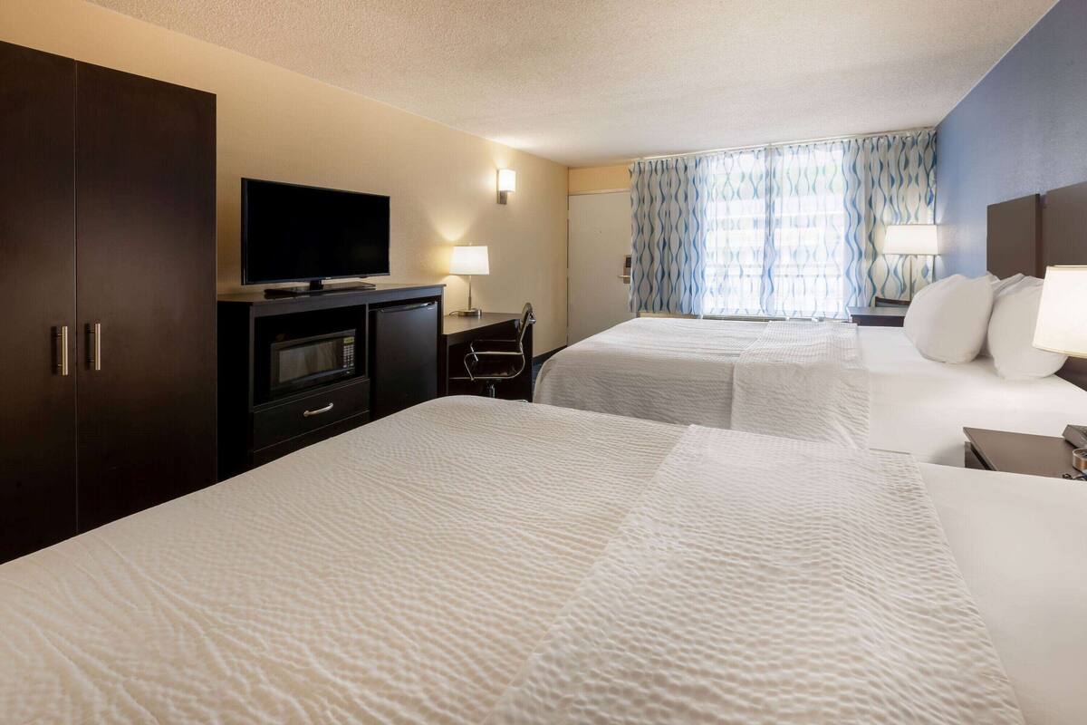 A hotel room with two beds, a TV, a desk, and a wardrobe.