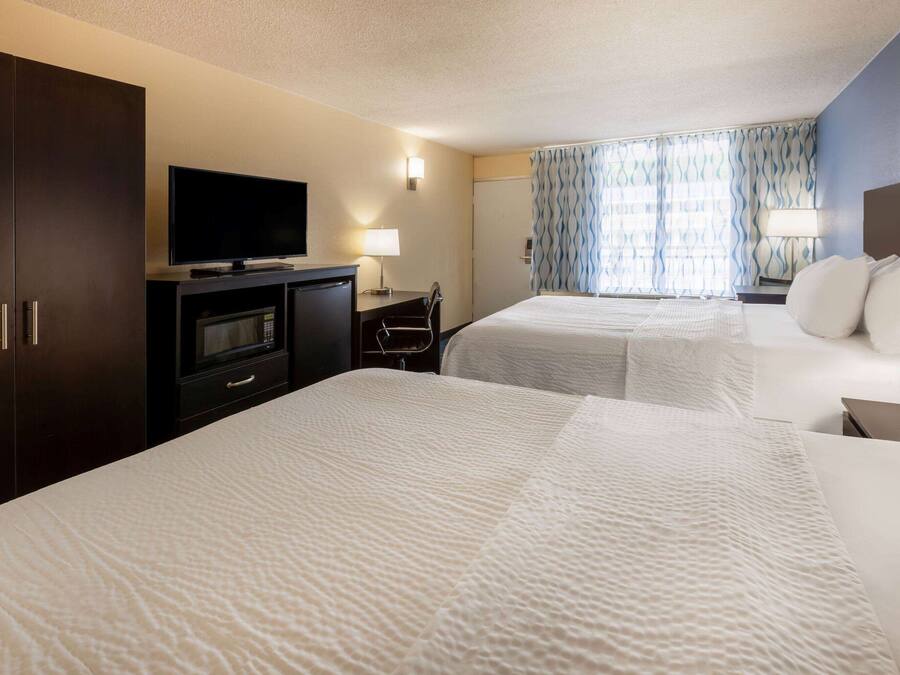 A hotel room with two beds, a TV, a desk, and a wardrobe.