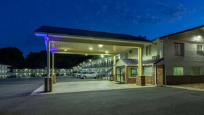 Un motel con área de estacionamiento techada, un pequeño vestíbulo y un edificio con techo plano.