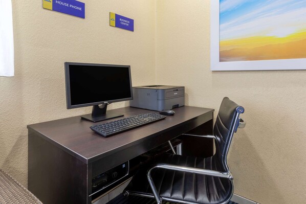 Une chambre d’hôtel équipée d’un bureau, d’un ordinateur, d’une imprimante et d’une chaise. Des panneaux indiquent l’emplacement d’un centre d’affaires et d’un téléphone d’intérieur.