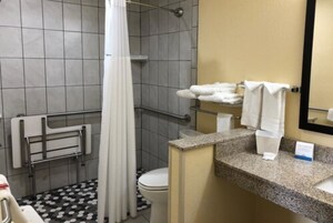 Un baño con ducha, inodoro y lavamanos con un perchero para toallas.