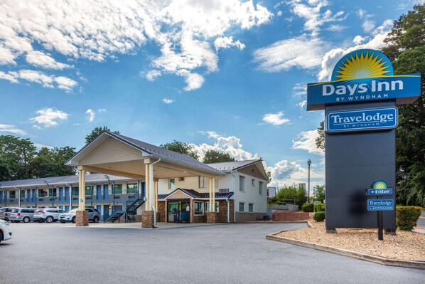 A Days Inn by Wyndham Travelodge with a covered entrance, multiple rooms, and a parking lot. - Days Inn by Wyndham Charles Town/Harpers Ferry (Charles Town)