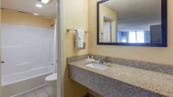 A bathroom with a bathtub, toilet, sink, and a large mirror.