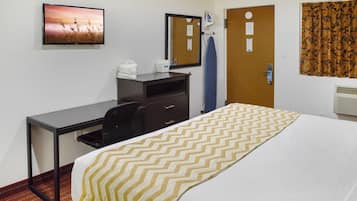 Una habitación de hotel con una cama, un escritorio, una silla, un espejo y un televisor.
