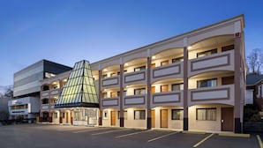 Un hôtel à plusieurs étages doté d’un atrium central, d’un parking et d’un bâtiment moderne attenant.