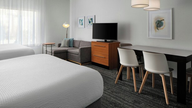 A hotel room with two beds, a desk with chairs, a television, and artwork on the walls. - TownePlace Suites by Marriott Florence (Florence)