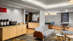 A modern kitchen with a coffee station, a dining area with a table and chairs, and a living area with a sofa and a coffee table. - TownePlace Suites by Marriott Florence (Florence)