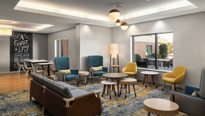 A modern lounge area with a sofa, armchairs, and small tables. - TownePlace Suites by Marriott Florence (Florence)