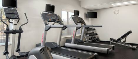 A gym with treadmills, elliptical machines, and a weight bench.