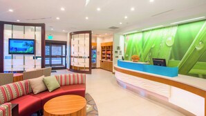 A reception area with a green wall, a reception desk, a sofa, and a TV.