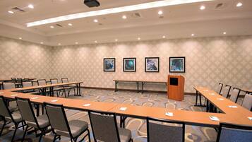 A conference room with a long table, chairs, a podium, and framed pictures on the wall.