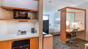 Habitación de hotel con microondas, cafetera y escritorio con silla.