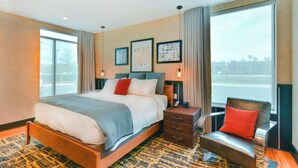 A modern hotel room with a large bed, a seating area, and a view of the outdoors.