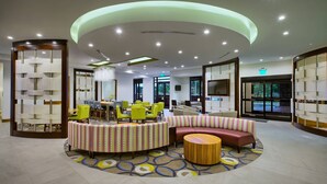 A modern lobby with a circular seating area, a reception desk, and a large chandelier.