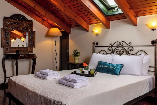 Una cama bien hecha con toallas, una bandeja con vasos y un cojín decorativo.