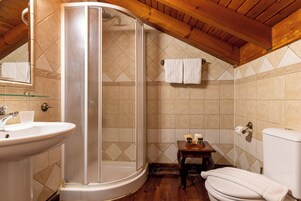 Un bagno con doccia vetro, lavandino, WC e un piccolo tavolo con articoli da toilette.