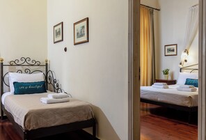 Ένα στρωμένο κρεβάτι με κεφαλάρι, ένα κομοδίνο με ένα φυτό και δύο φωτογραφίες σε κορνίζες στον τοίχο.