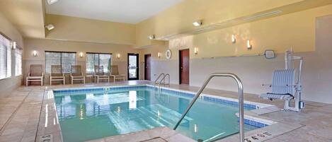 Une piscine intérieure à l’eau claire, dotée d’un sol carrelé et d’un escalier pour y accéder.