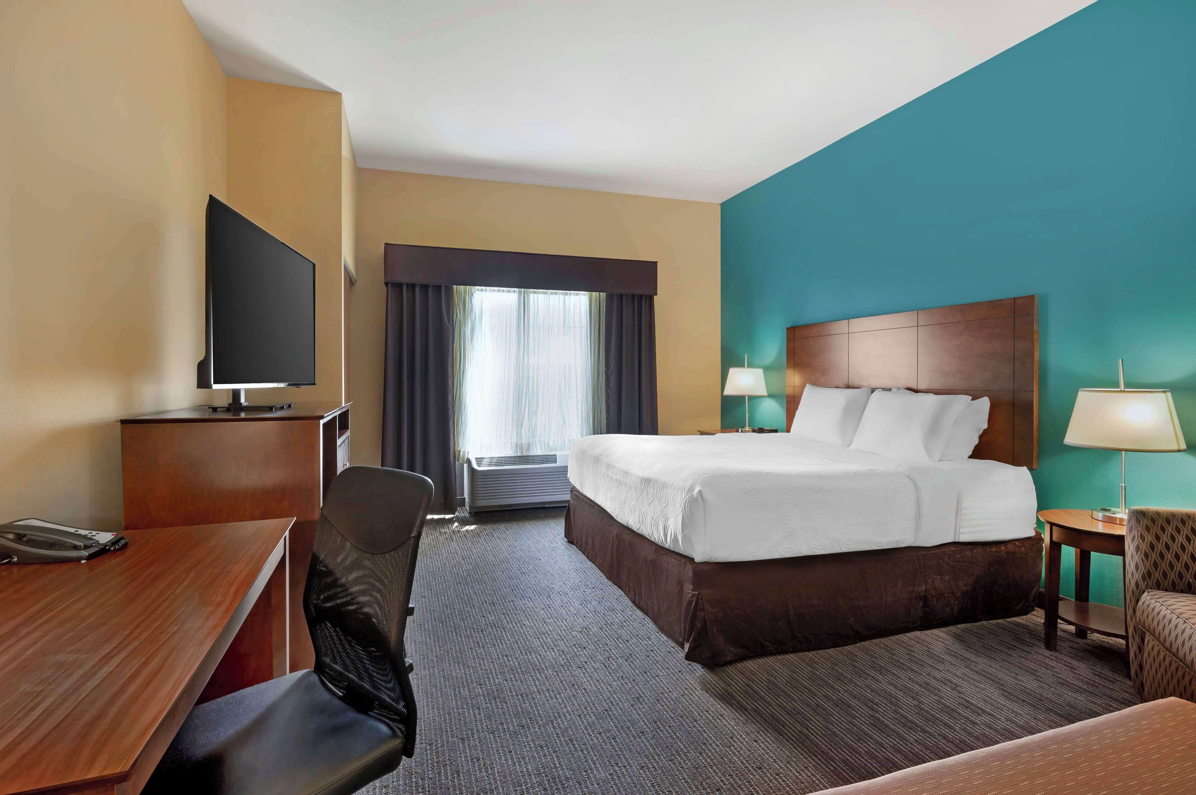 Ein Hotelzimmer mit Bett, Schreibtisch, Stuhl, Fernseher und Lampen.