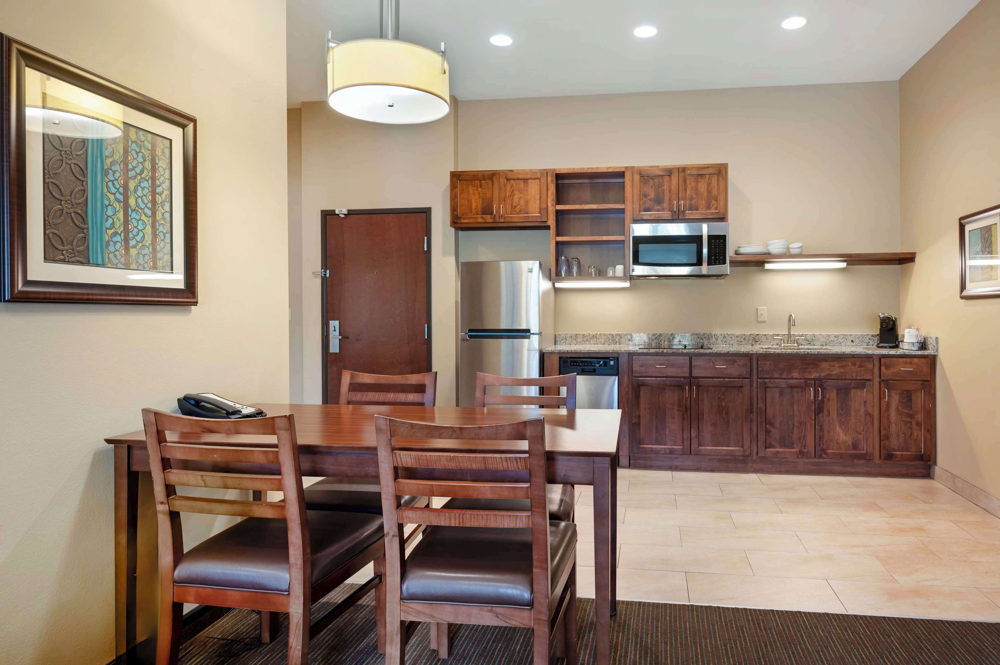 A modern kitchen with wooden cabinets, stainless steel appliances, and a dining area with a table and chairs.