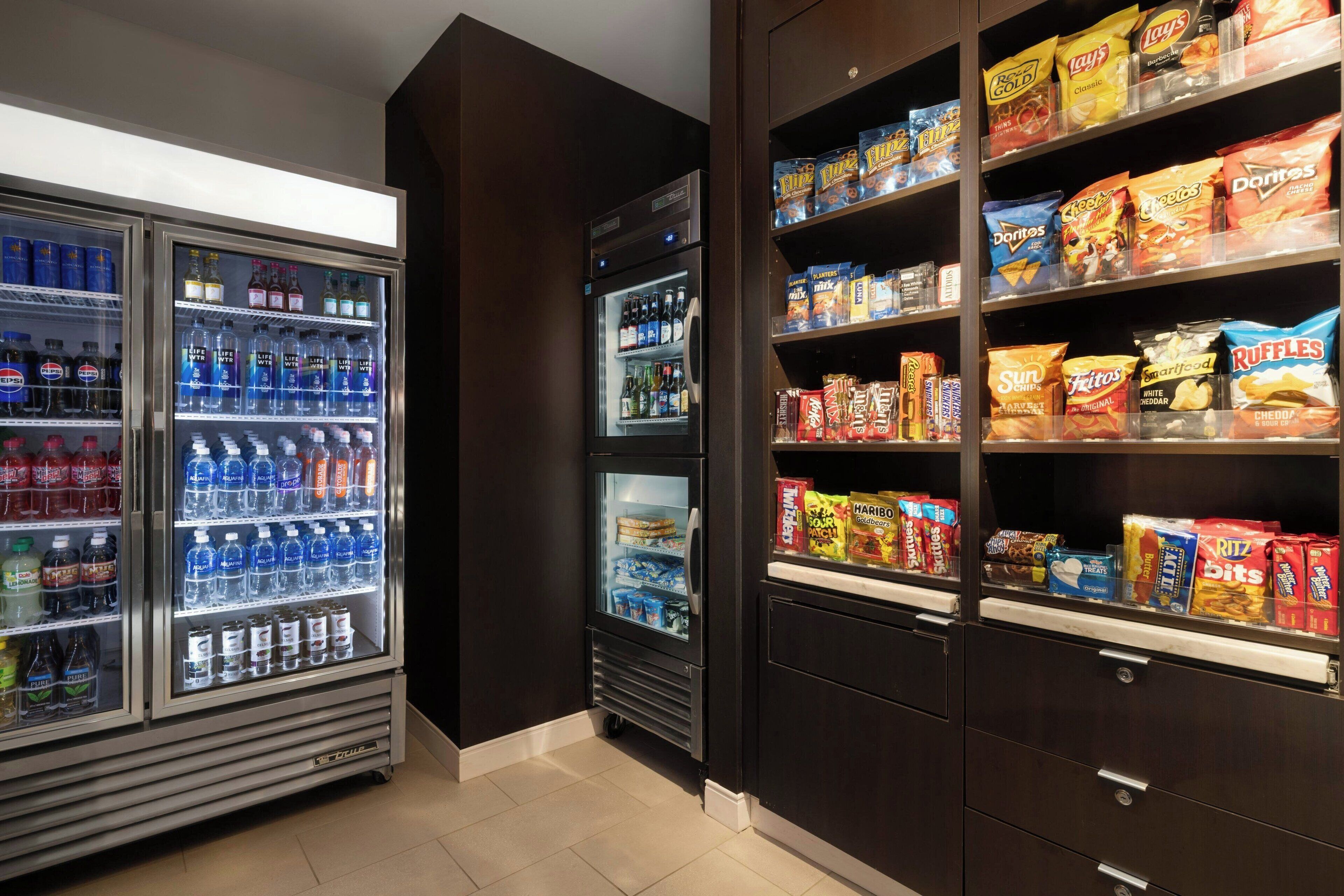 Un área de venta automática con diversas opciones de bocadillos y bebidas, como papas fritas y bebidas embotelladas.
