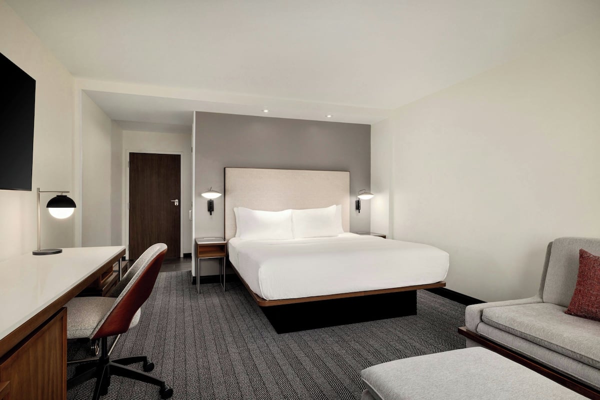Une chambre d’hôtel avec un lit, un bureau, une chaise et un canapé.