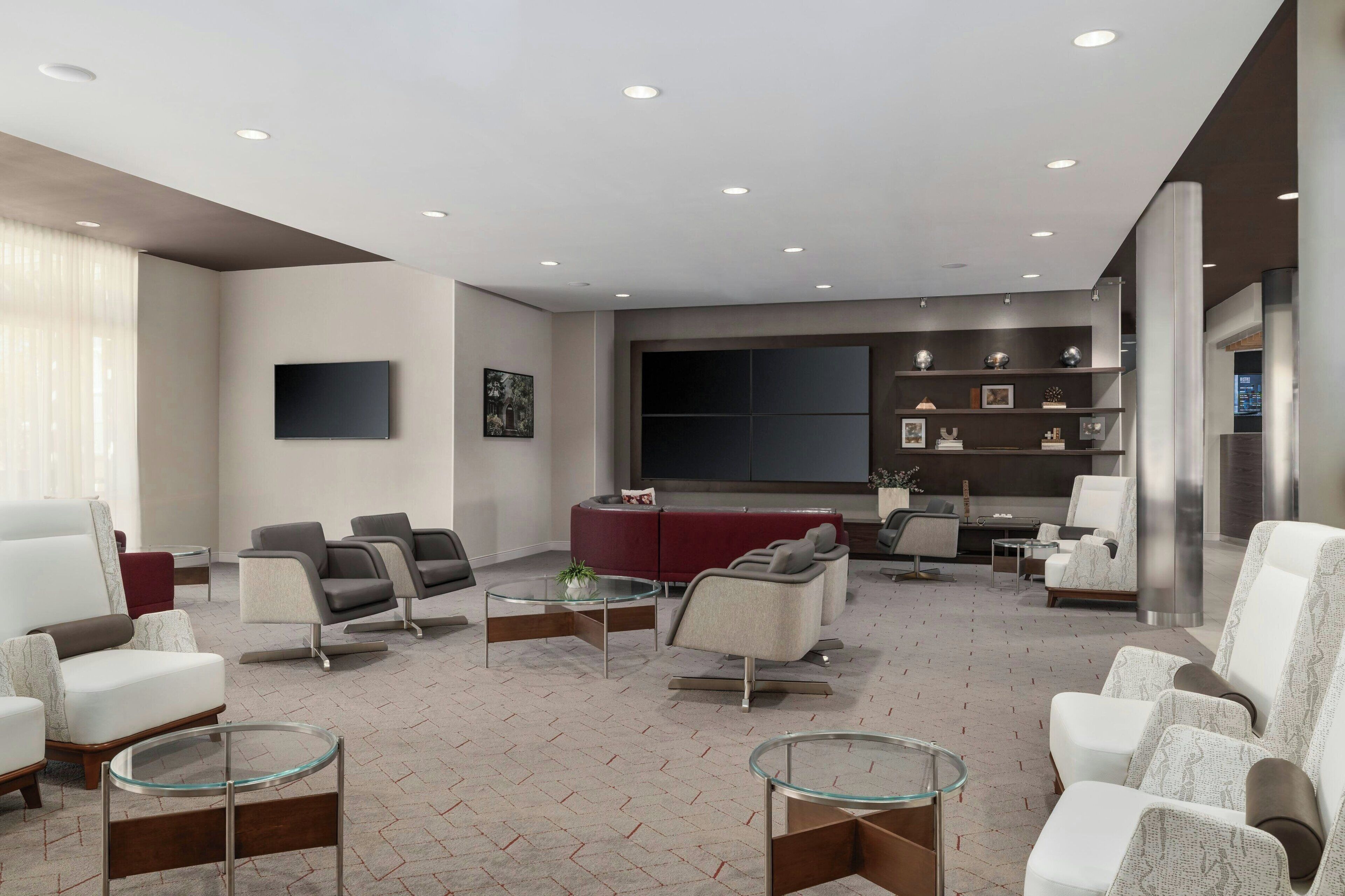 Una sala moderna con un sofá modular, sillones y una mesa de centro de vidrio.