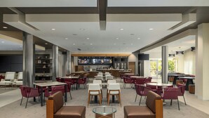 A modern restaurant with high ceilings, recessed lighting, and a central bar area. - Courtyard by Marriott Starkville MSU at The Mill (Starkville)