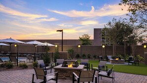 An outdoor patio with a fire pit, seating, and umbrellas. - Courtyard by Marriott Starkville MSU at The Mill (Starkville)