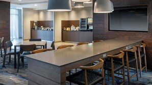 A modern hotel lobby with a long bar, seating area, and a kitchen in the background. - Fairfield Inn & Suites Bowling Green (Bowling Green)
