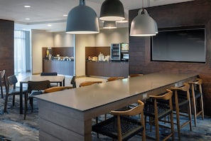 A modern hotel lobby with a long bar, seating area, and a kitchen in the background. - Fairfield Inn & Suites Bowling Green (Bowling Green)