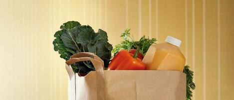 A kitchen counter with a paper bag containing vegetables and a bottle.