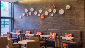 Un ristorante moderno con un lungo bancone, sedute imbottite e una parete decorativa con motivi circolari.