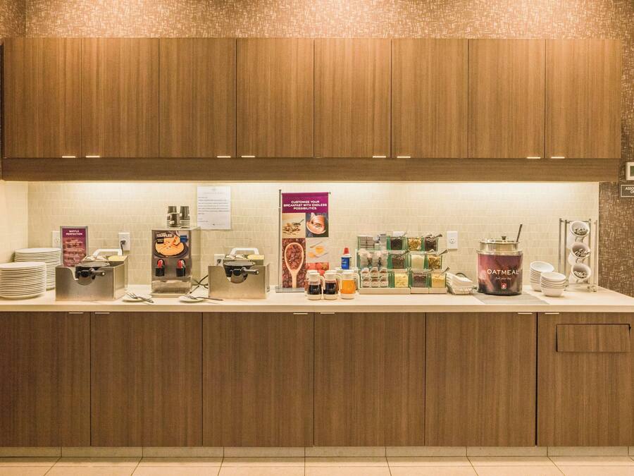 A breakfast bar with wooden cabinets, a coffee machine, and various breakfast items.