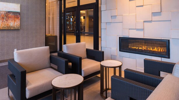 A modern lounge area with wicker furniture, a fireplace, and a glass door leading to a dining area.