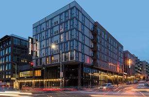 A modern hotel with a glass facade, multiple floors, and a prominent entrance.