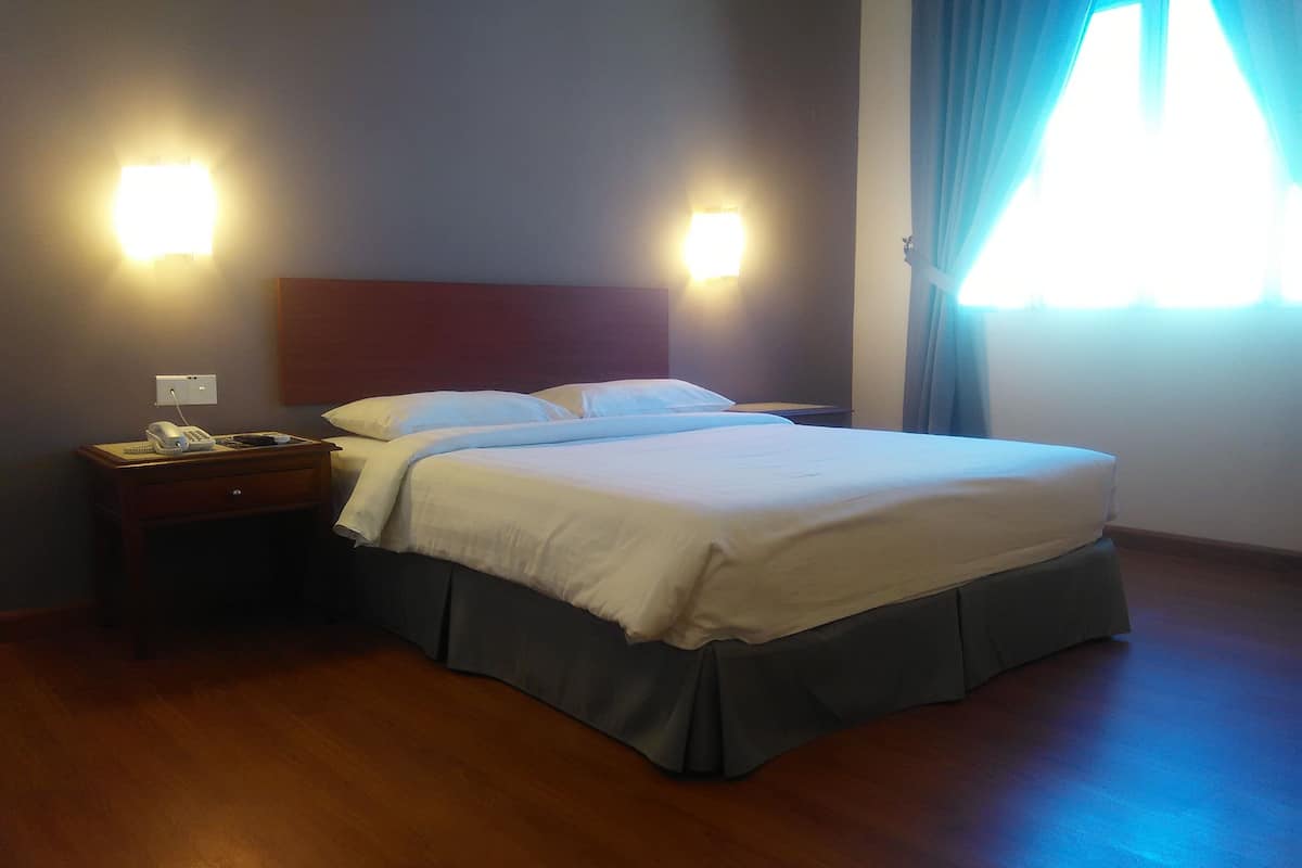 A hotel room with a bed, a nightstand, a telephone, and two wall-mounted lights.