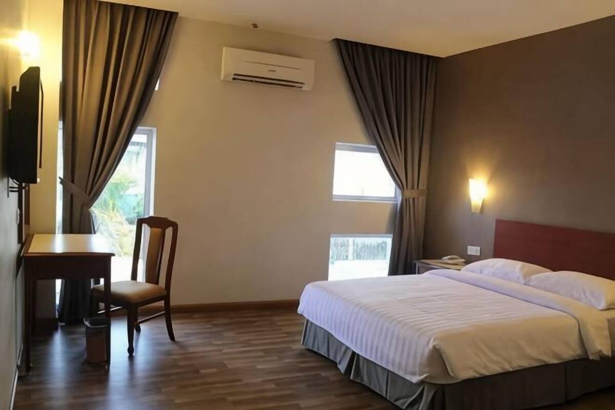 A hotel room with a bed, a desk, a chair, and a TV.