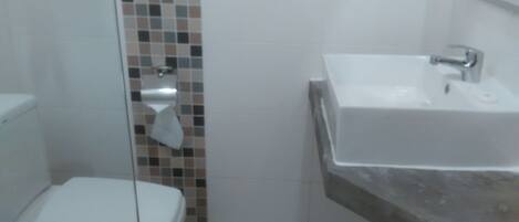 A bathroom with a toilet, a sink, and a tiled wall.